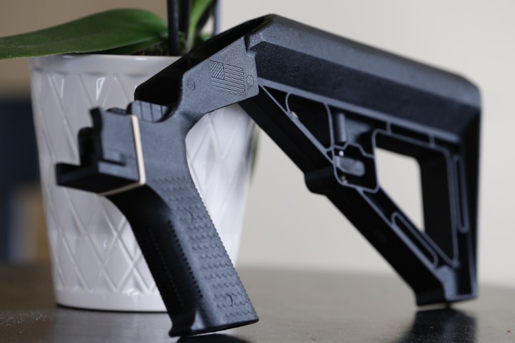 close-up photo of bump stock on a table with a potted plant in the background