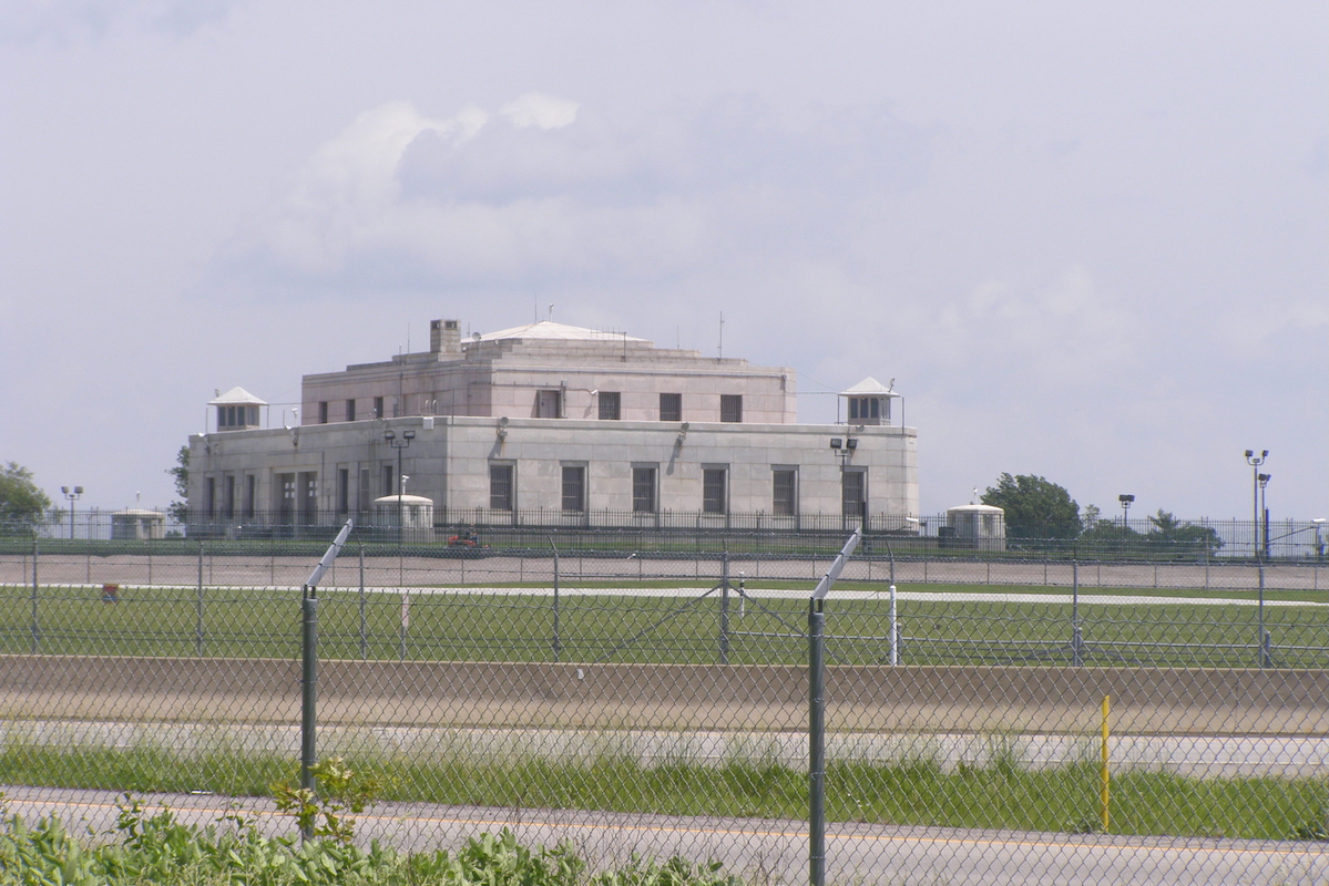 Photo U.S. Bullion Depository at Fort Knox taken from a distance behind a fence, on a cloudy day
