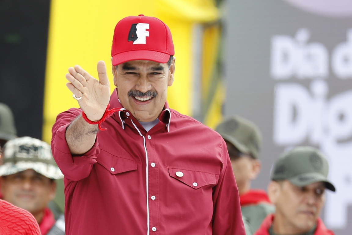 Nicolas Maduro on a stage outdoors waving to a crowd