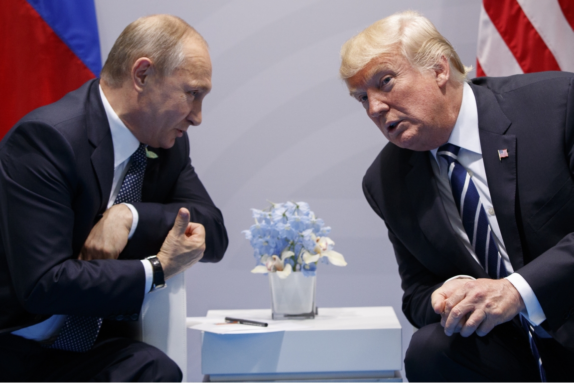 Vladimir Putin and Donald Trump speak to each other while seated at a conference in 2017